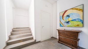 A staircase leading to a door, a wooden dresser with drawers, and a colorful abstract painting on the wall. - GuestHost - Cozy 60 sqm apartment, located on the first floor of a building without an elevator.The accommodation is situated in a strategic location, allowing you to reach the main points of interest within a short walking distance or by public transpor (Udine)