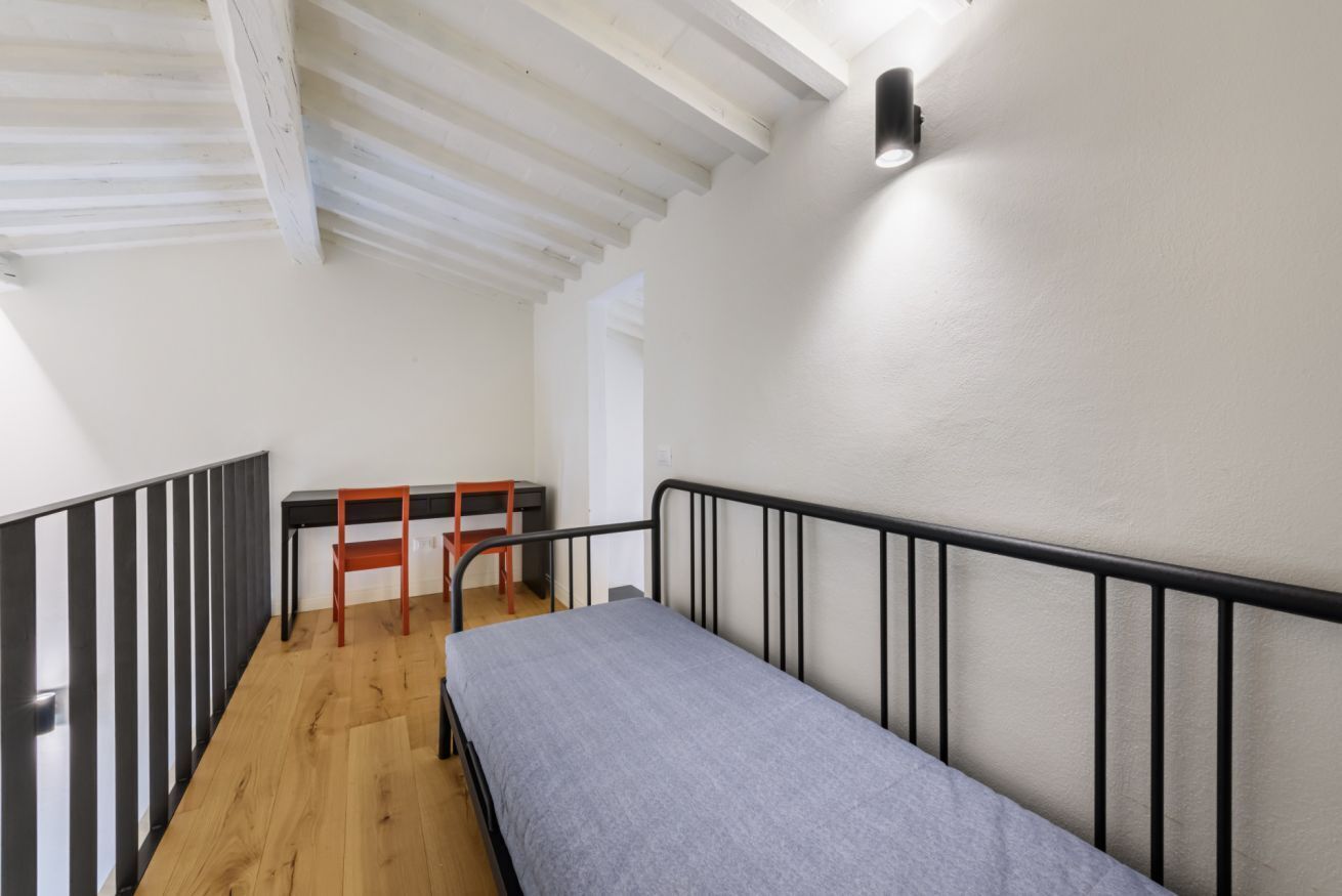 A dormitory room with a single bed, a desk, and a chair.