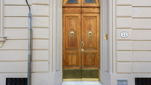 A double wooden door with a brass handle, a small window above it, and a number '34' on the wall to the right. - Orcagna by MMega Homes and Villas (Florence)