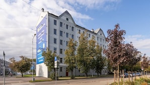 A multi-story hotel with a prominent blue advertisement on the side. - Sunny 1BR Apartment near Park & Stadium (Riga)