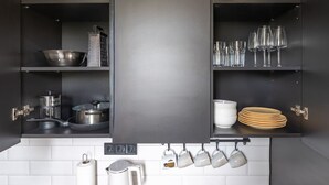 A modern kitchen with dark cabinetry, stainless steel appliances, and neatly organized utensils and dishes. - Sunny 1BR Apartment near Park & Stadium (Riga)