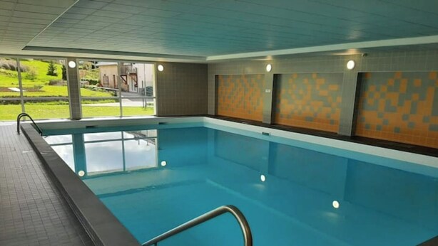 Una piscina interior d'aigua cristal·lina blava, parets i sòl revestits de rajola.