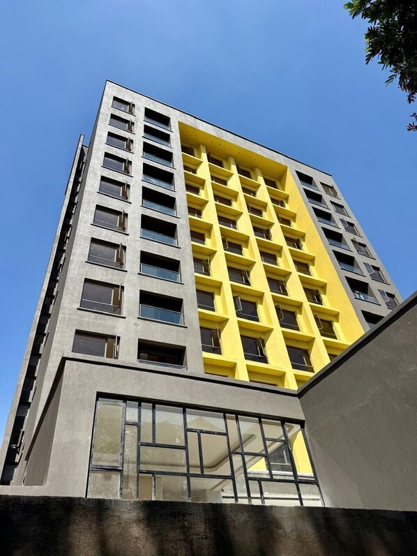 Un immeuble de grande hauteur doté d’une architecture moderne, caractérisé par une combinaison de couleurs gris et jaune.