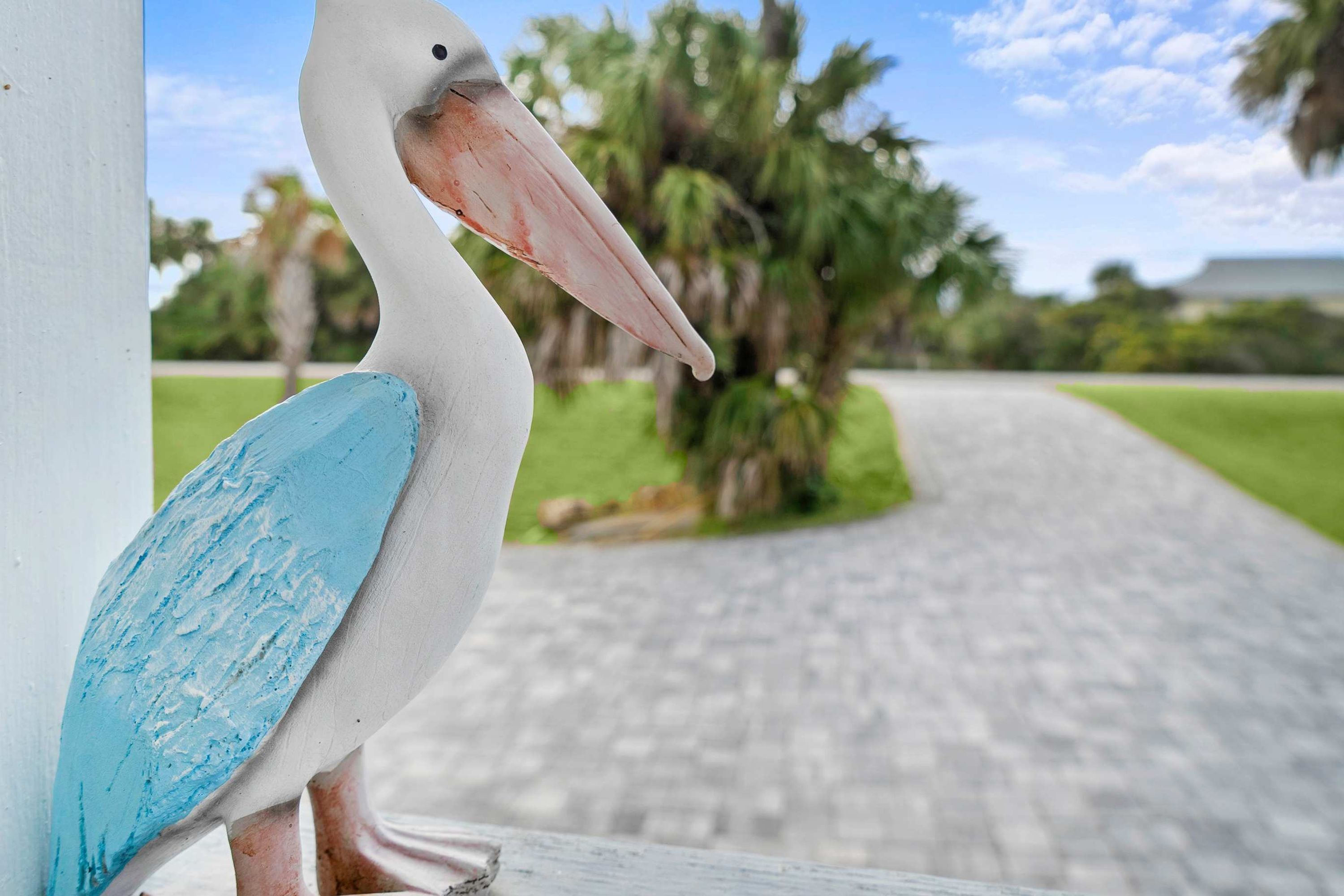 Een vogelbeeld met een witte romp en blauwe vleugel, geplaatst tegen een witte paal.