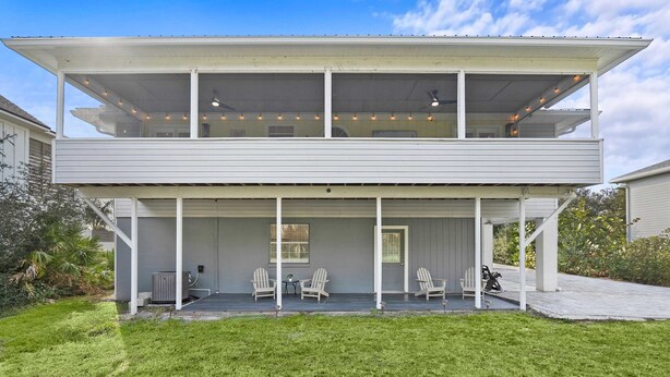 Une maison à deux étages dotée d’un porche abrité, d’un espace salon extérieur et d’un appareil de climatisation visible.