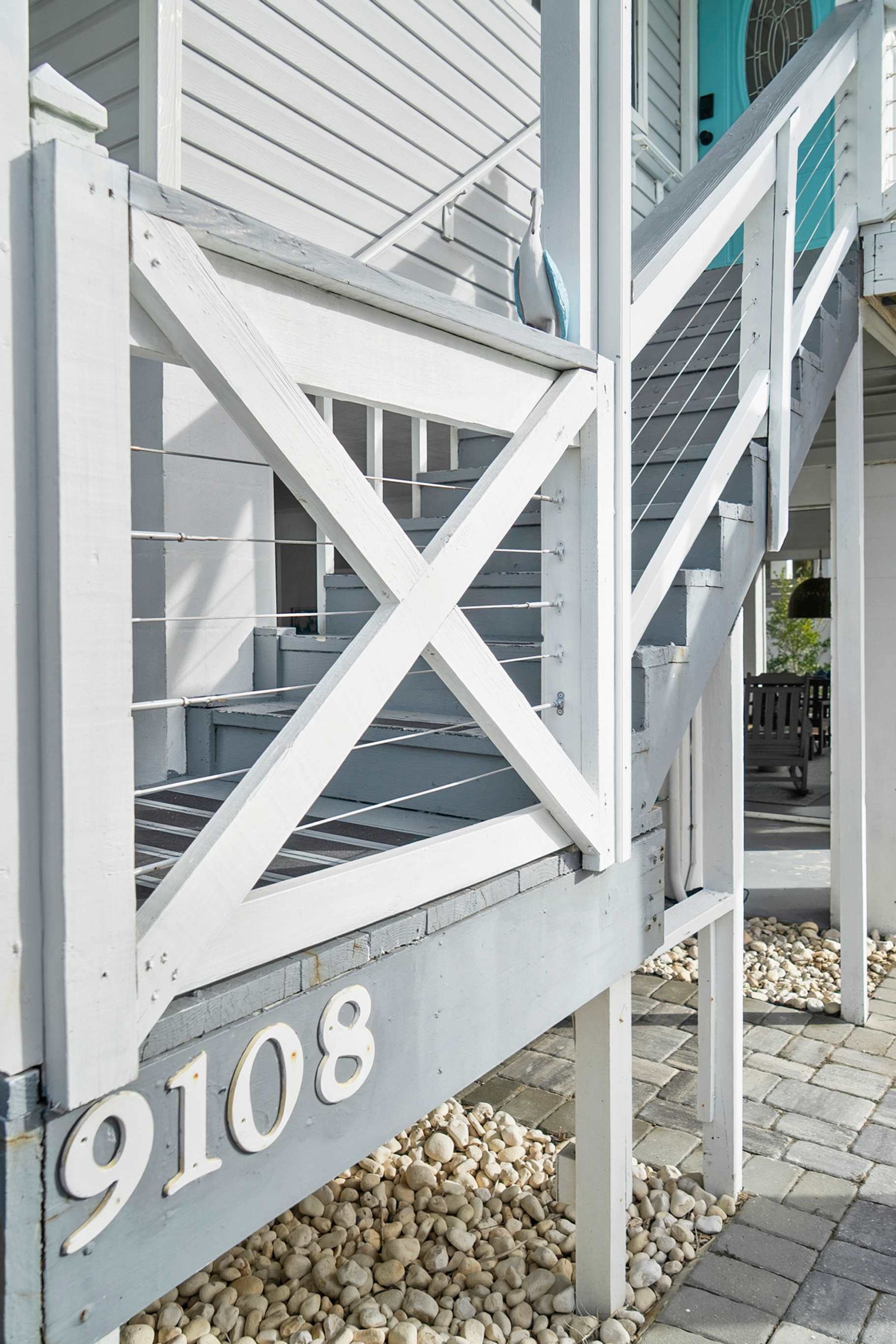 A white wooden staircase with a railing leading to a door marked with the number 9108.
