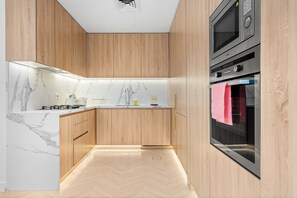 Eine moderne Küche mit Holzschränken, einer Marmor-Spritzschutzleiste und Edelstahlgeräten.