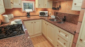 A compact kitchen with a gas stove, a microwave, a toaster, and a sink. - Franbols Cottage (Halifax)
