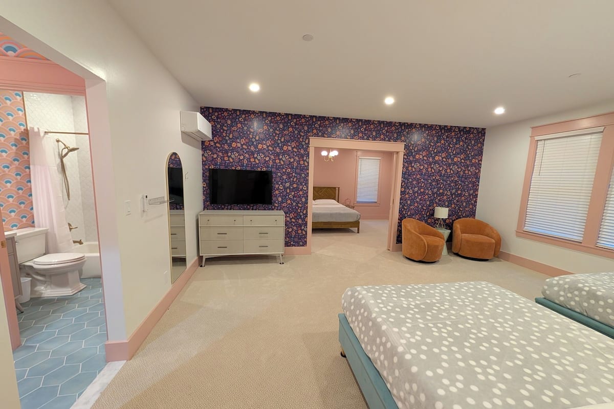 Un dormitorio con cama, cómoda, televisor y zona de ducha.