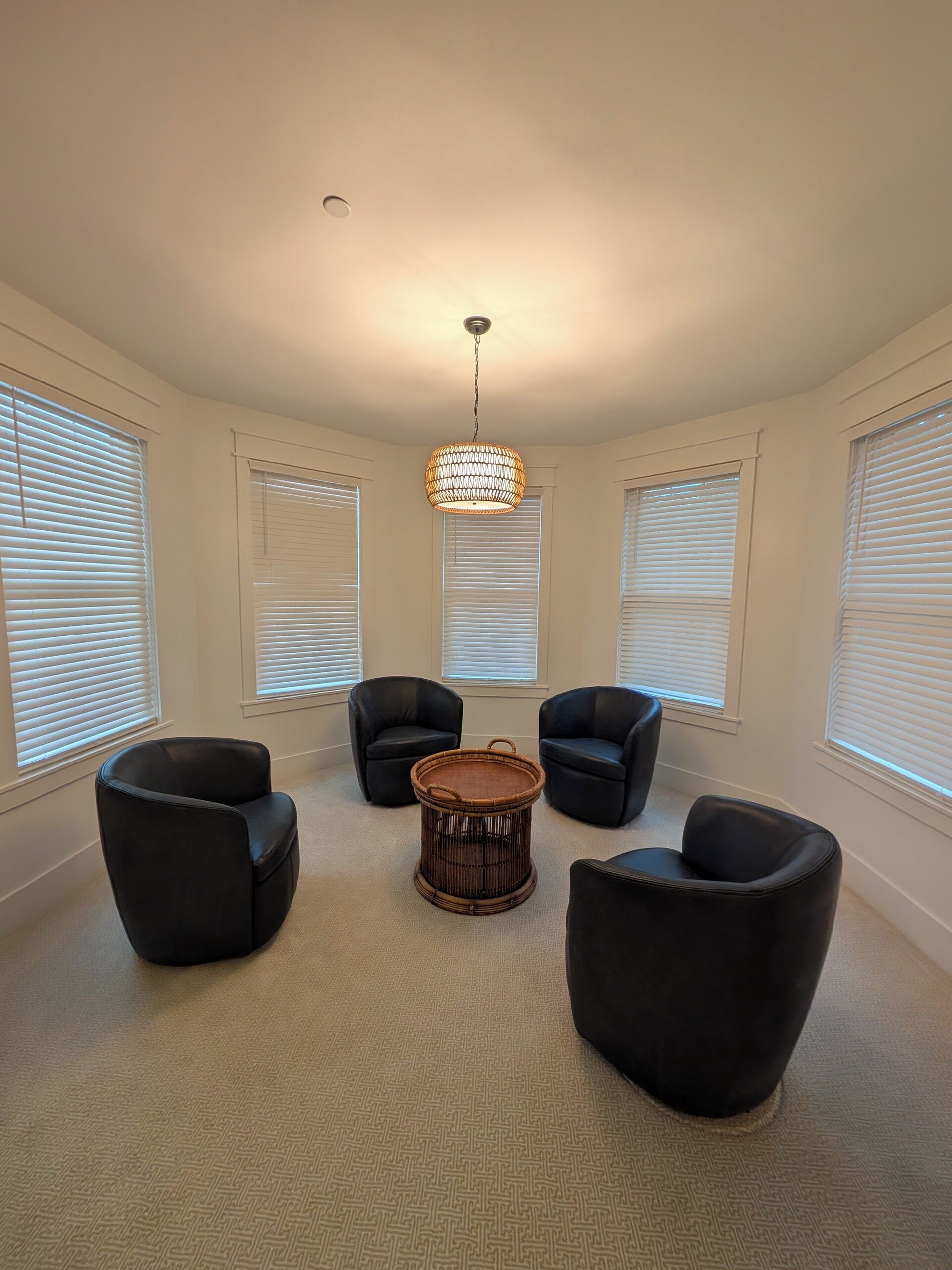 A room with four black leather chairs arranged around a central round table.