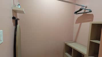 Um armário pequeno e bem arrumado, com barra para pendurar roupas, prateleiras e gavetas.