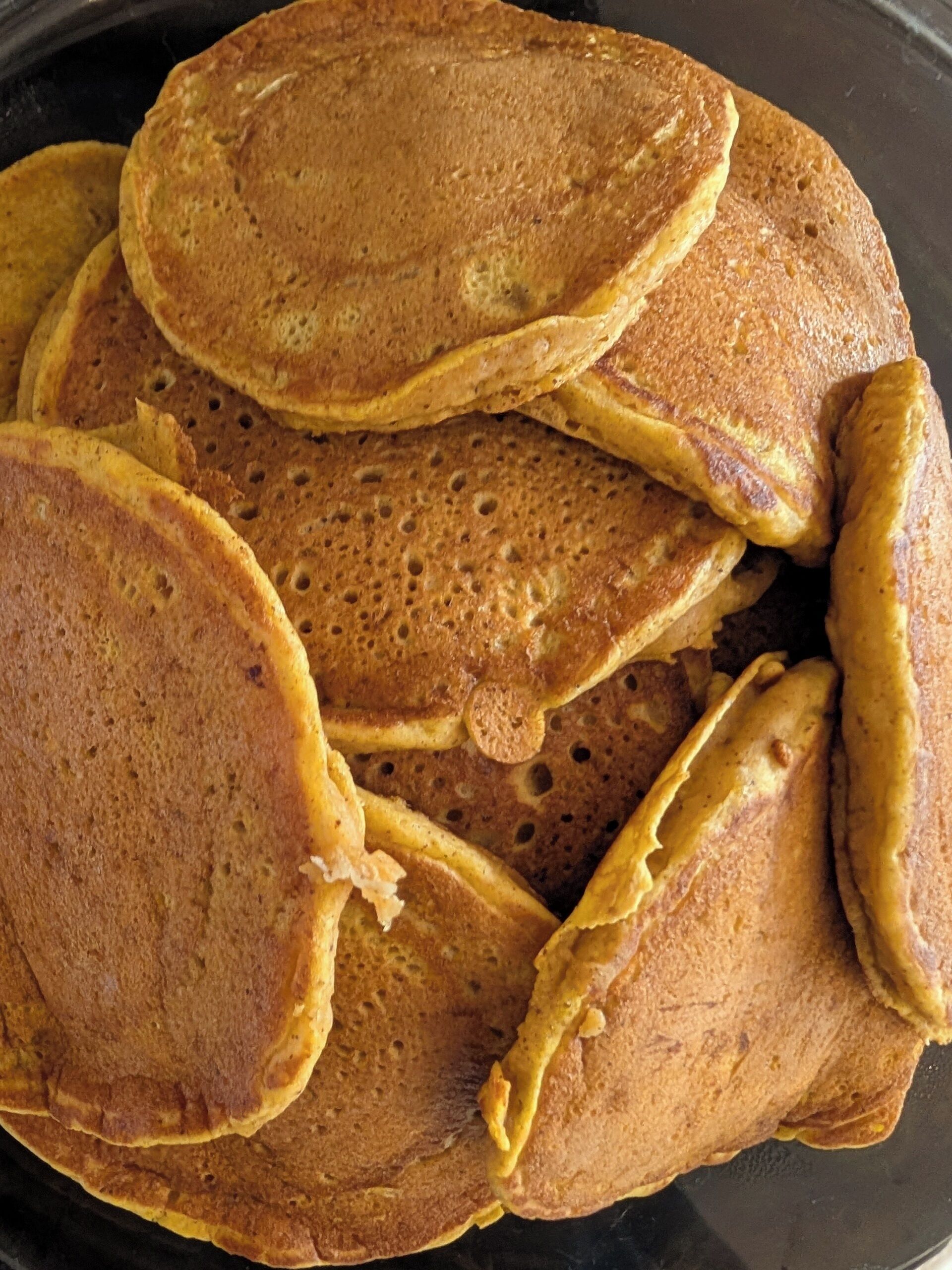 A stack of pancakes on a black plate.