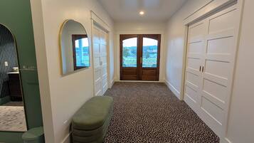 A hallway with a leopard print carpet, white walls, a bench, and a door leading to a balcony with a view.