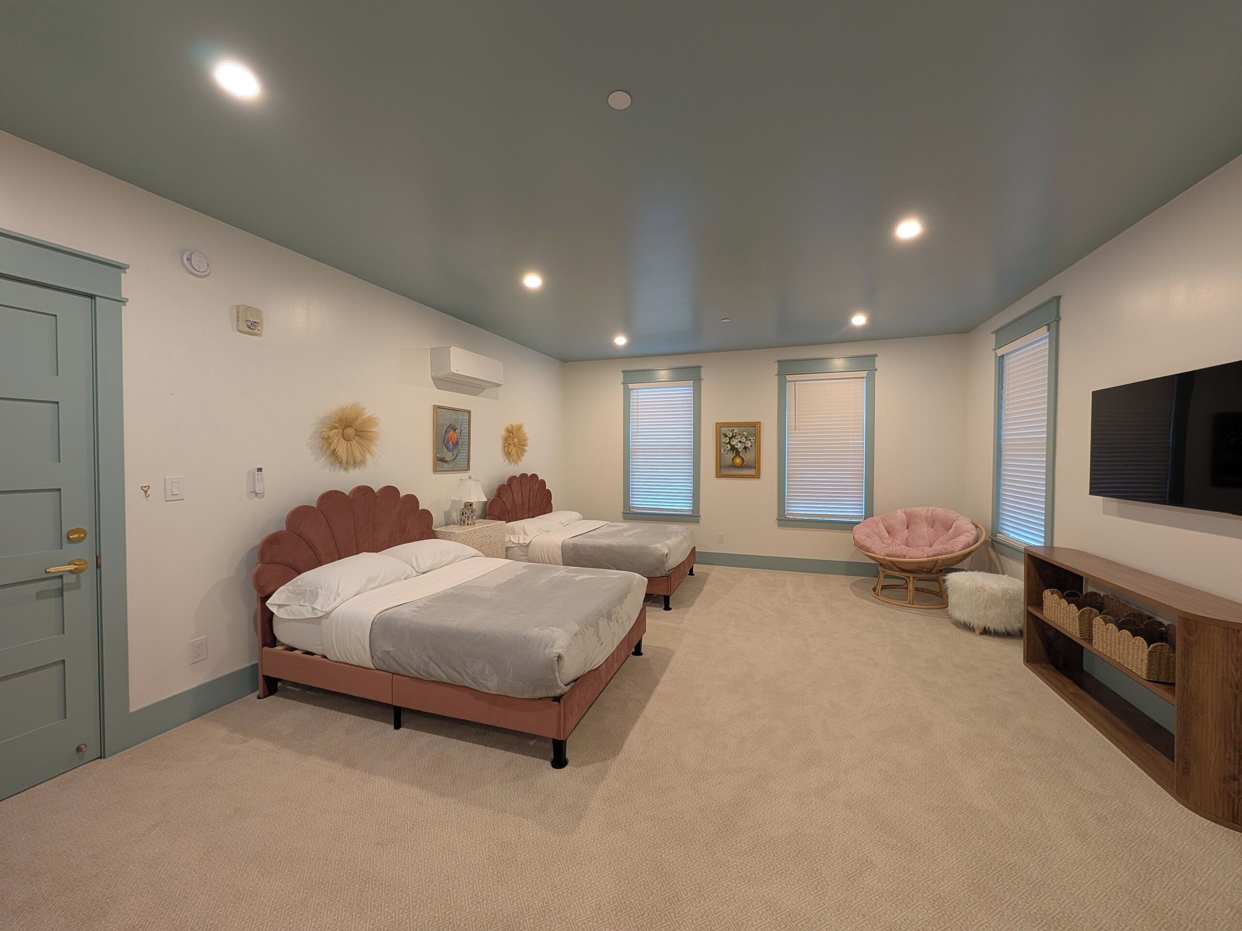 A bedroom with two beds, a TV, and a seating area.