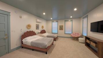 A bedroom with two beds, a TV, and a seating area.