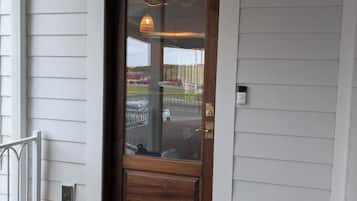 A wooden front door with a glass panel, a porch with wooden steps, and two pumpkins on the ground.