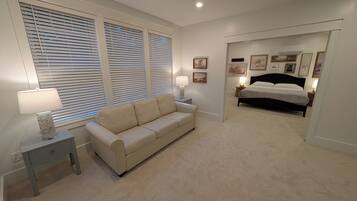 Un dormitorio con cama, sofá y mesita de noche con lámpara.