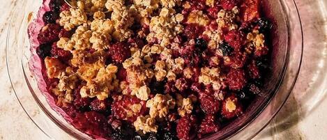 A bowl of fruit crumble with a spoon.