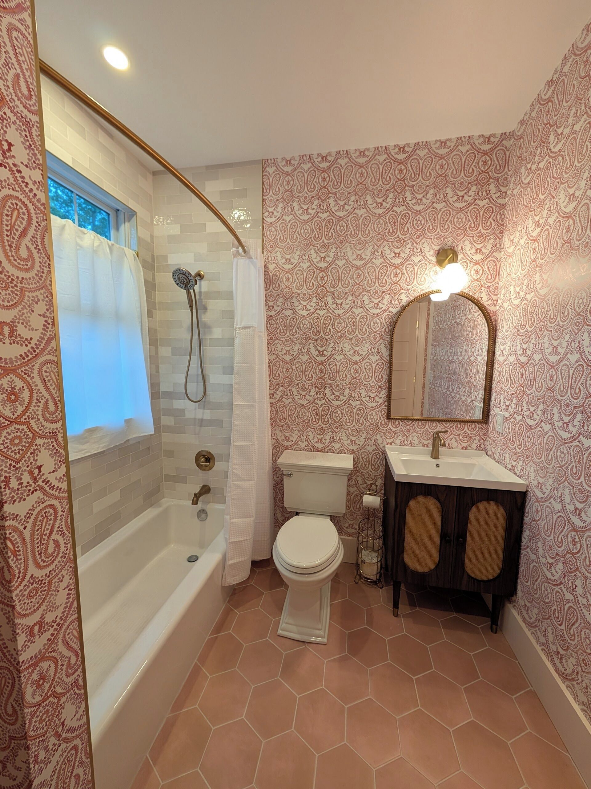 A bathroom with a shower, toilet, sink, and mirror.