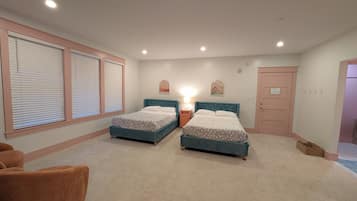 Ein Schlafzimmer mit zwei Betten, einem Nachttisch, einem Sessel und einer Tür.