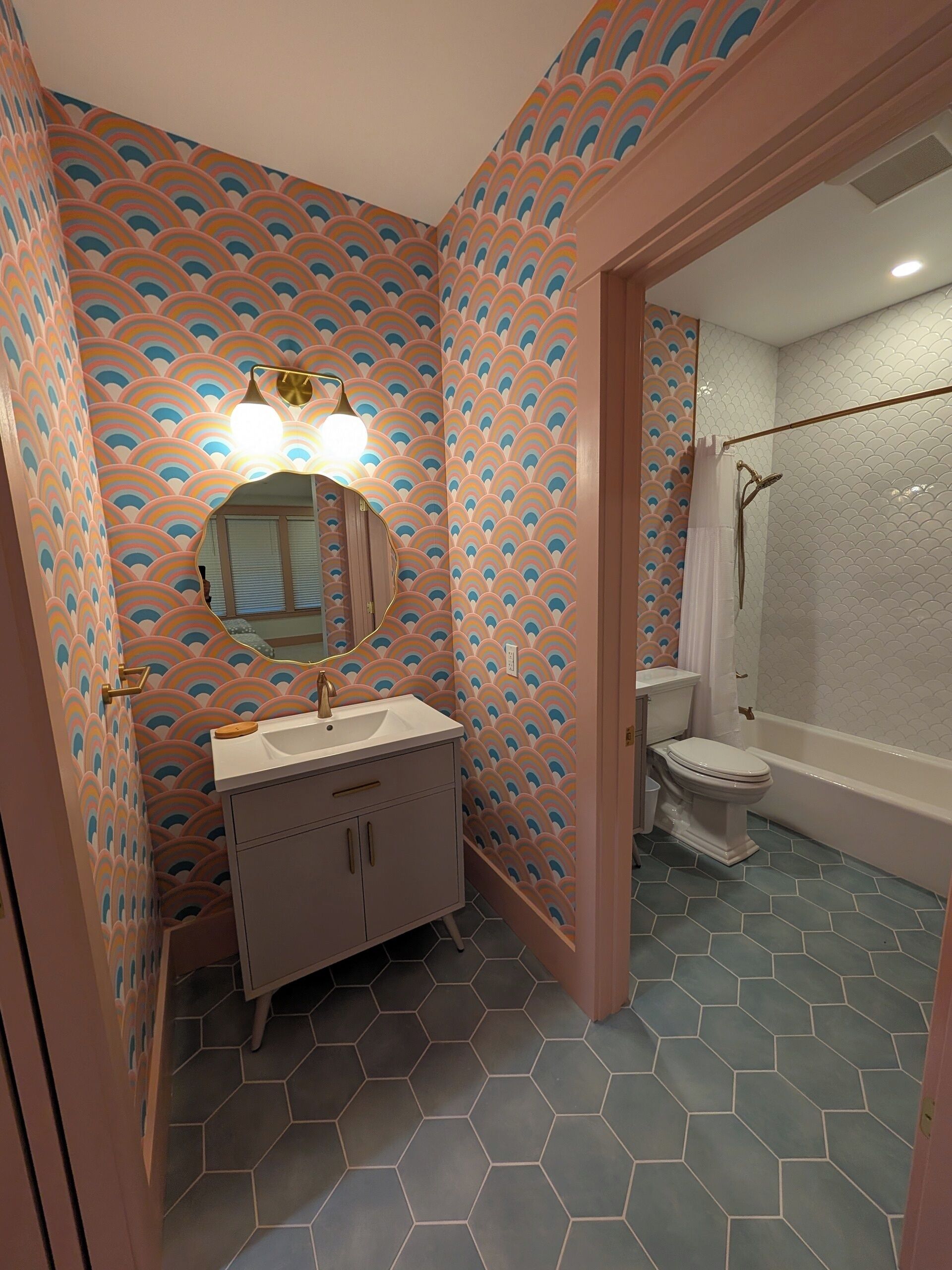 A bathroom with a vanity, sink, mirror, and shower area.