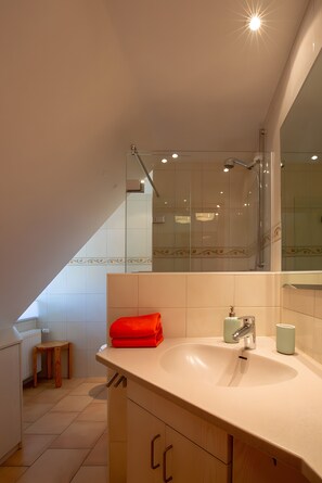 A modern bathroom with a large mirror, a sink, and a shower. - Apartment 'Appelhus Cox' with Shared Terrace, Shared Garden and Wi-Fi (Pellworm)