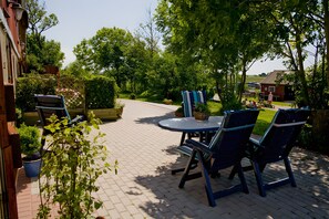 Eine Terrasse mit Sitzgelegenheiten, einem runden Tisch und Blumentöpfen.