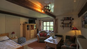 Een gezellige woonkamer met een bank, fauteuil, houten kast en een televisie.