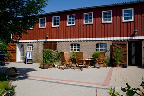 A red building with multiple windows and a paved courtyard with outdoor furniture. - Apartment 'Fewo Appelhof Ingrid Marie' with Private Terrace, Shared Garden and Wi-Fi (Pellworm)