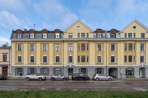 A row of yellow buildings with multiple windows and a storefront. - Dark & Moody Mid Century Apartment (Riga)