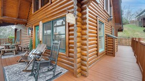 A log cabin with a porch, rocking chairs, and a sign that reads "The Porch Sit & Relax". - Resort-style Smokies Cabin w/ Hot Tub + Game Room (Sevierville)
