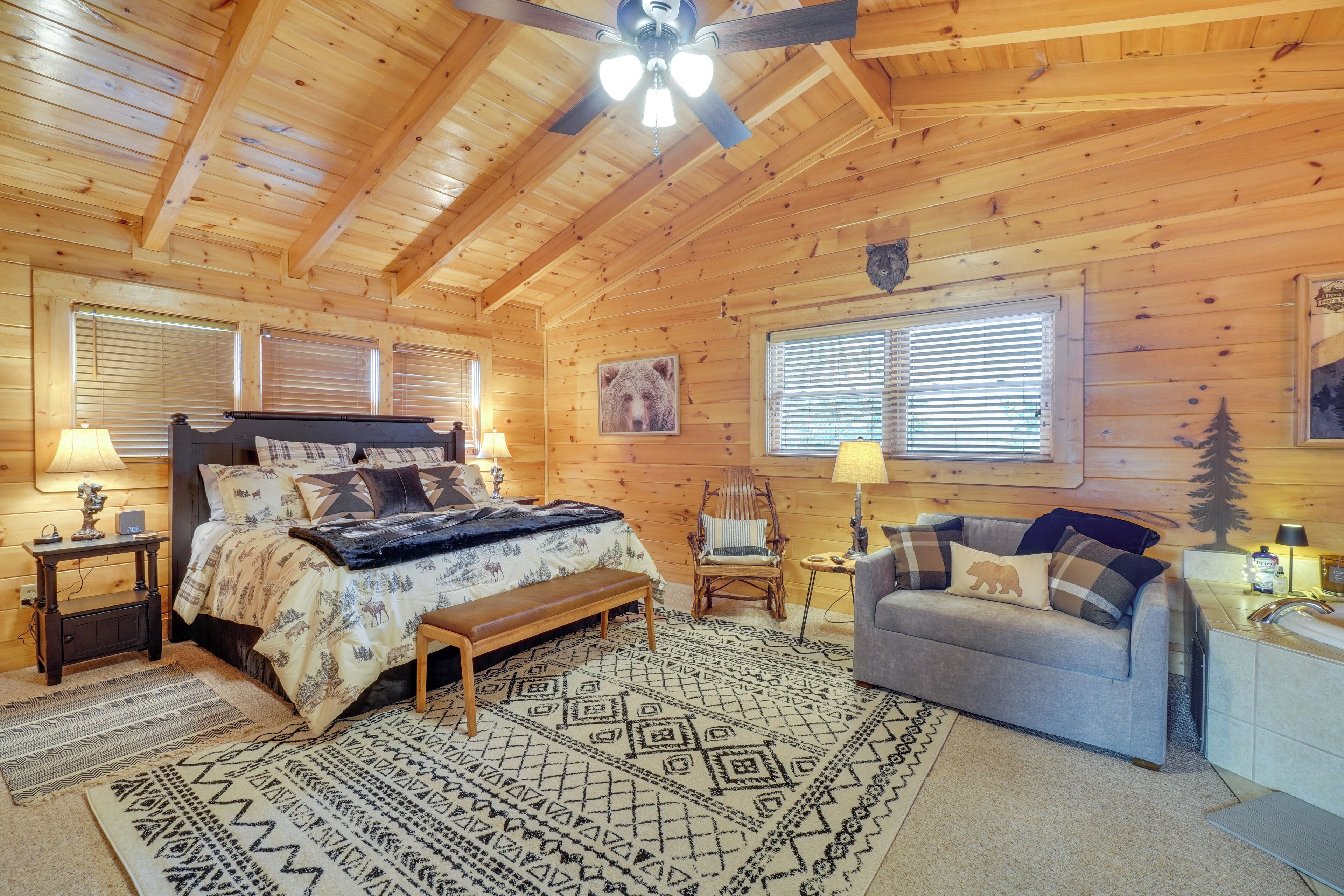 A cozy log cabin bedroom with a bed, a chair, a sofa, and a desk.