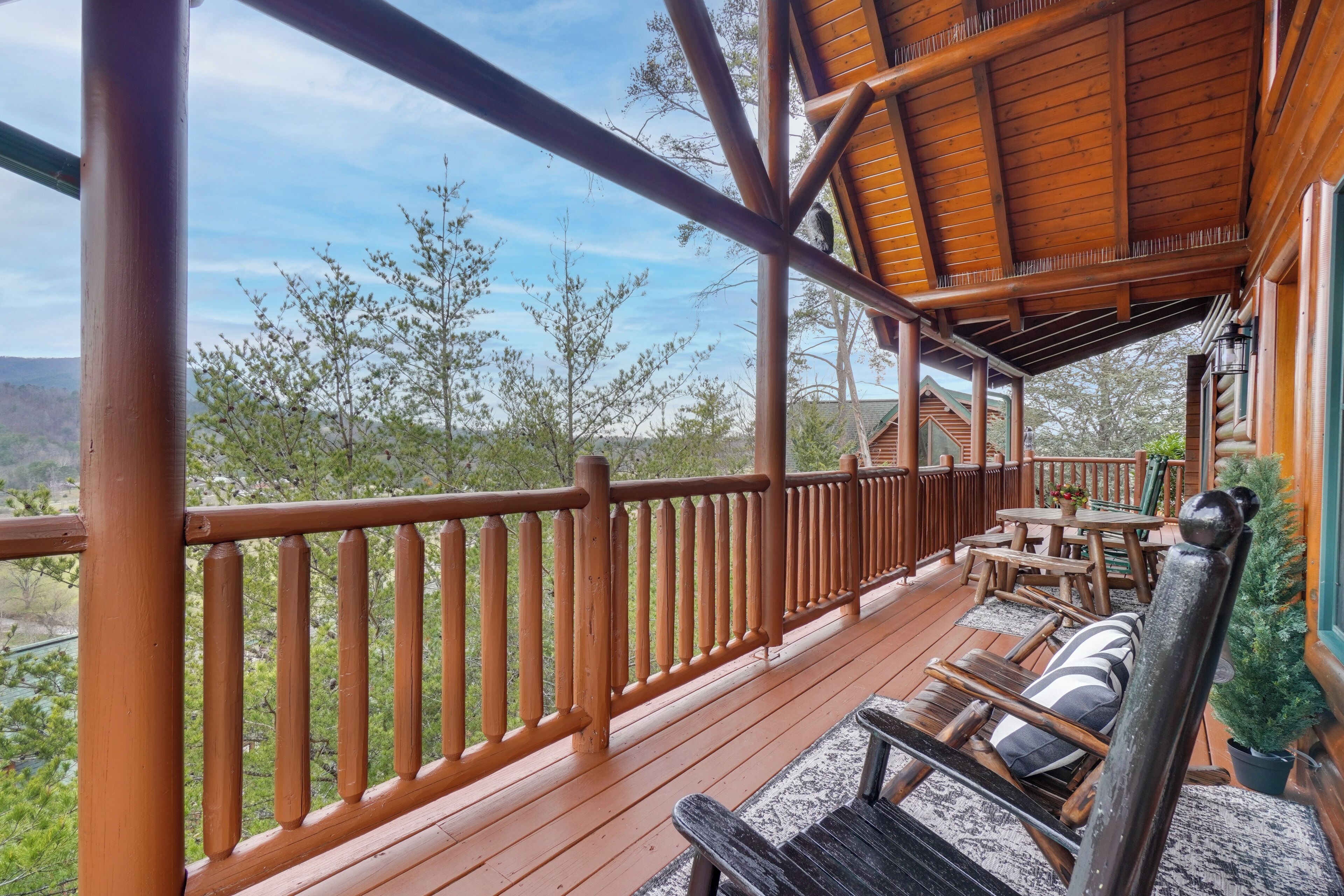 Um deck de madeira com guarda-corpo, móveis de exterior e vista para a paisagem circundante.