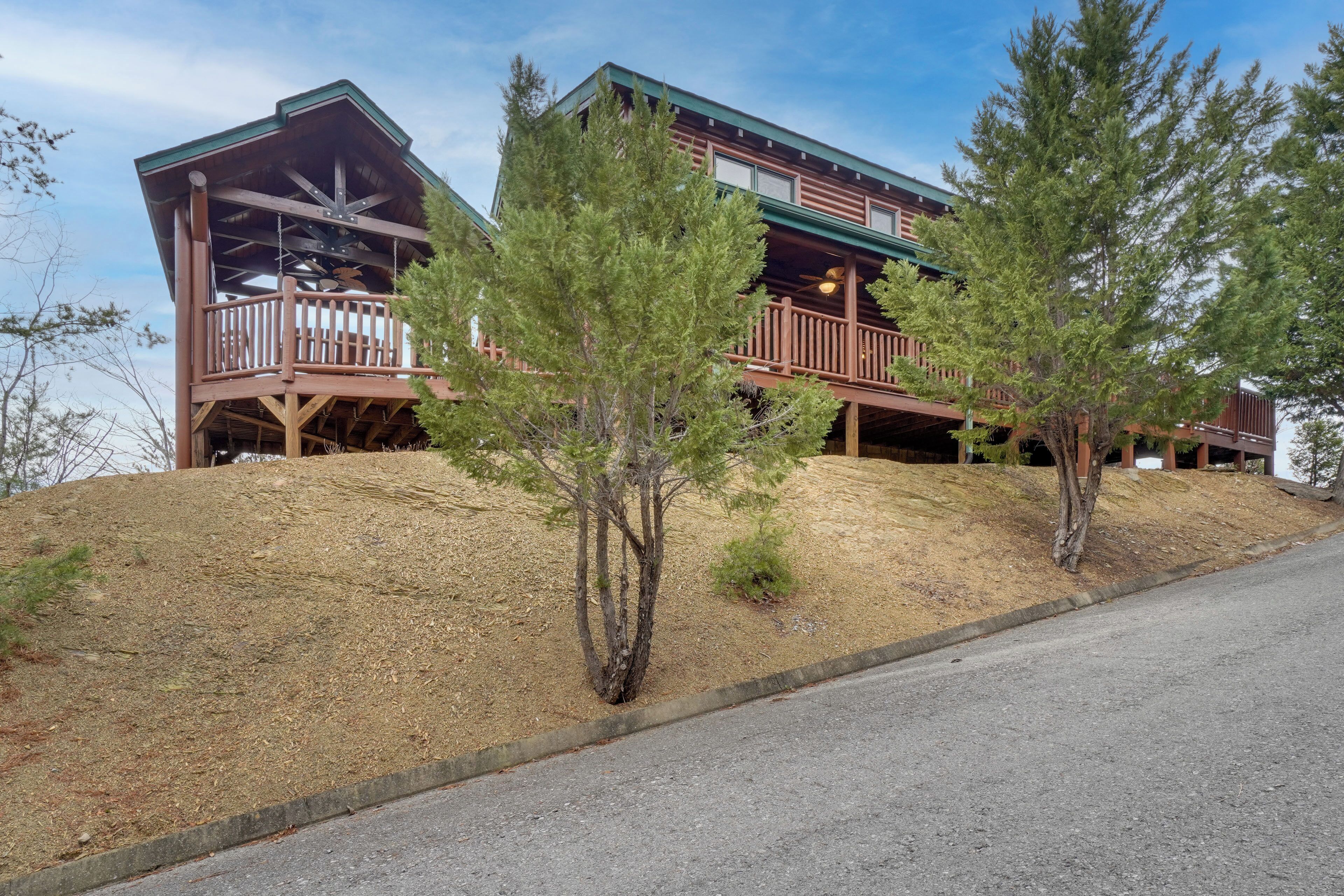 A two-story log cabin with a balcony and a covered porch.