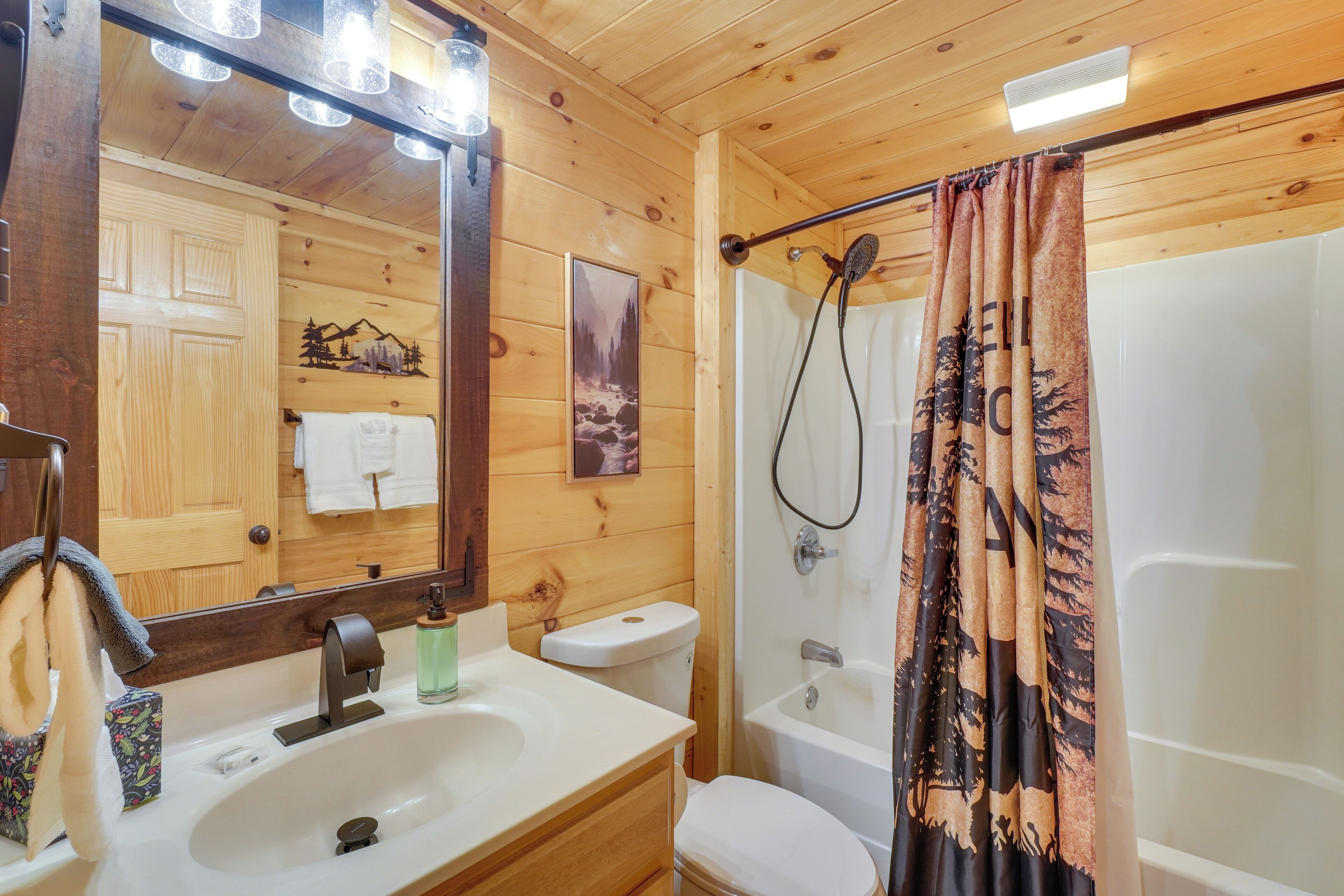 Baño de cabaña de madera con lavamanos, inodoro y ducha.