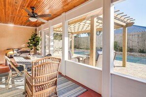 Ein überdachter Patio-Bereich mit Esstisch, Korbstühlen und Deckenventilator.
