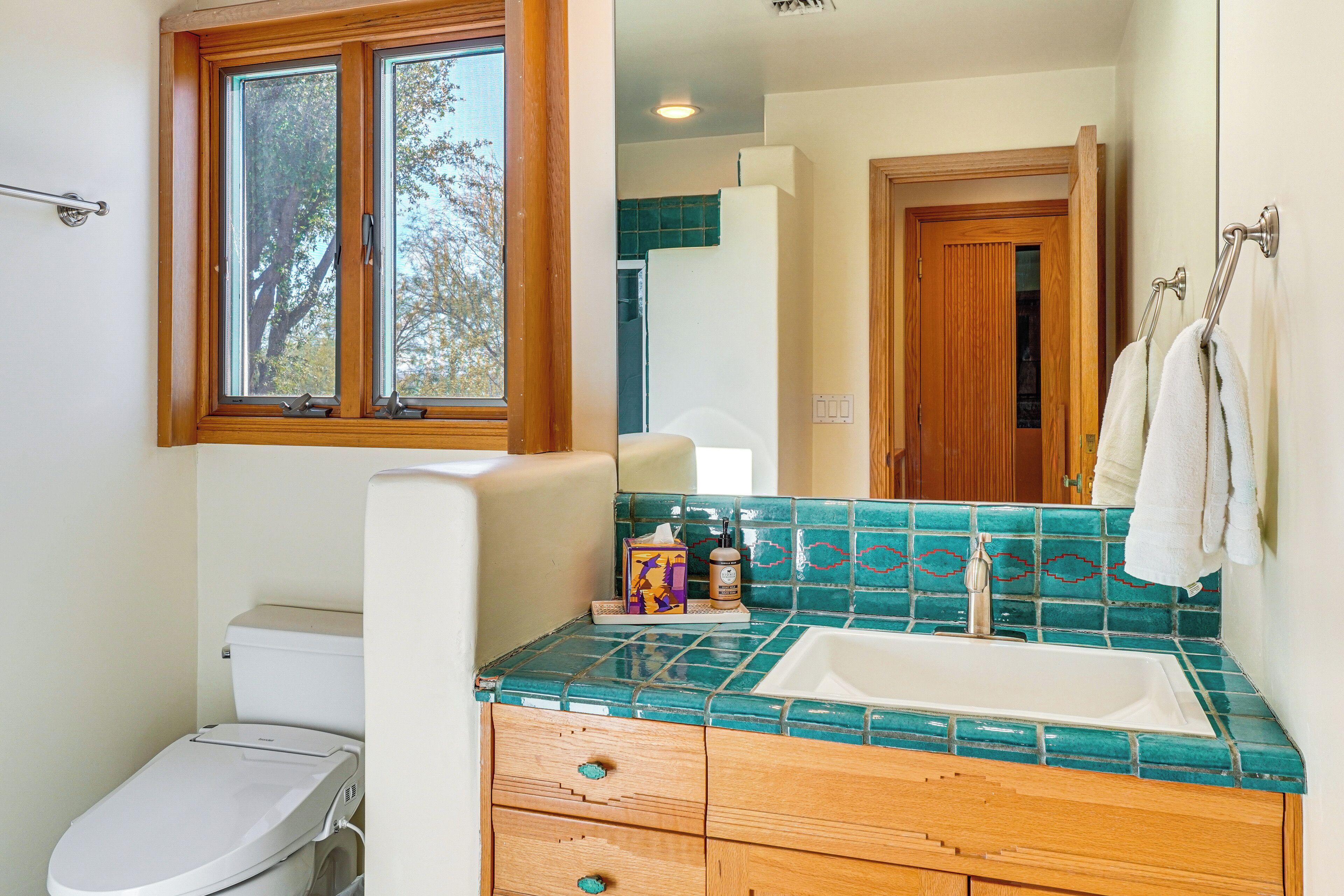 A bathroom with a toilet, sink, and wooden vanity.