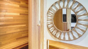 Een houten vloer met een verticale houten wandpaneel en een rond spiegel met een kwastdecoratie, bevestigd aan de muur.