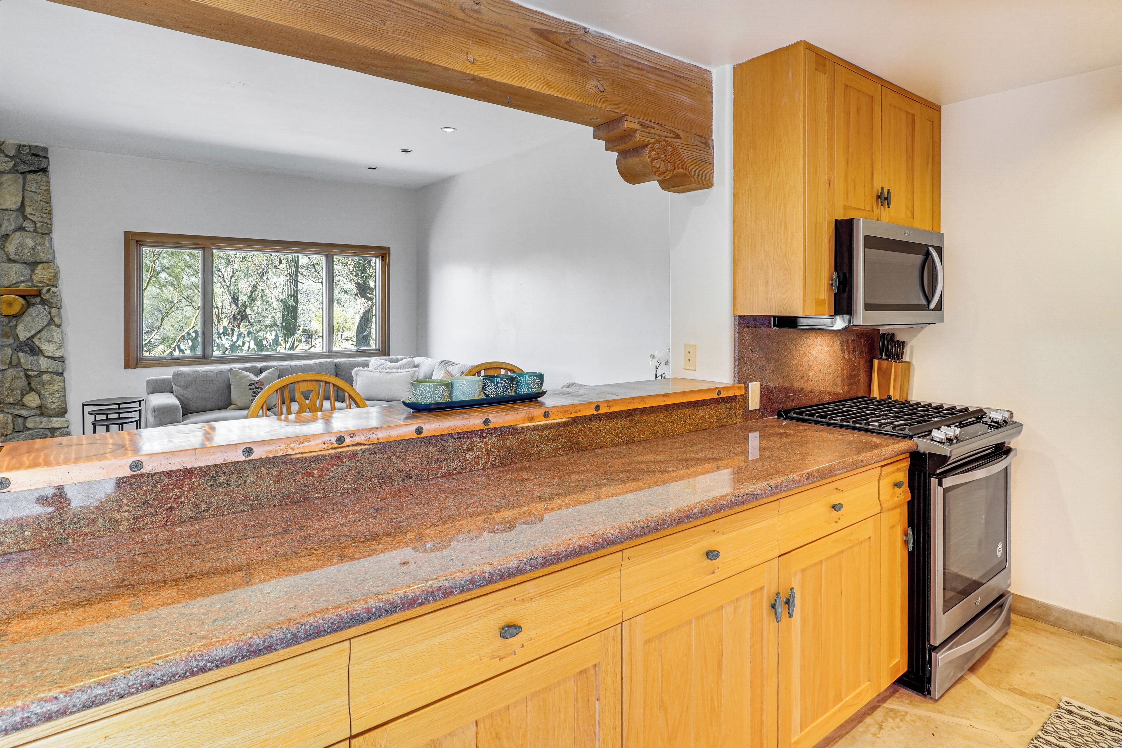 A kitchen with granite countertops, wooden cabinets, a built-in microwave, and a stove.