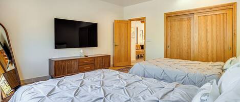 A bedroom with a bed, a TV, a wardrobe, and a ceiling fan.