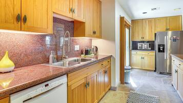 Una cocina con armarios de madera, encimeras de granito, electrodomésticos de acero inoxidable y lavavajillas.