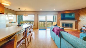 A modern kitchen with a dining area, a living room with a fireplace, and a balcony with a view. - Stunning Ocean Views! Oregon Coast Condo (Gearhart)