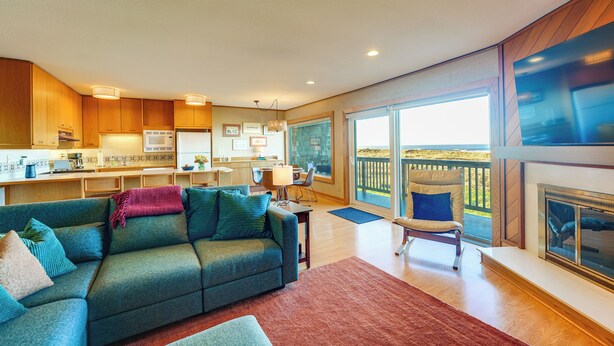 A modern living room with a sofa, a dining area, and a kitchen. - Stunning Ocean Views! Oregon Coast Condo (Gearhart)