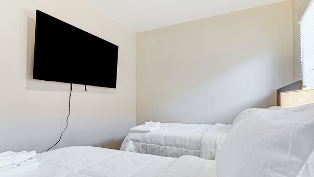 A hotel room with two beds, a flat-screen TV mounted on the wall, and a window with blinds. - Walkable Haven 1 Mi to Dtwn Phoenix & Chase Field! (Phoenix)
