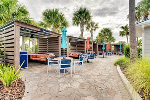 A patio area with outdoor seating, covered by wooden structures, and surrounded by palm trees. - Resort-style Retreat w/ Amenities Galore Near Wdw! (Davenport)