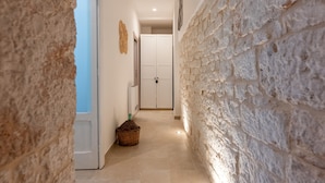 Un pasillo con paredes de piedra, una puerta blanca y una cesta de mimbre en el suelo.