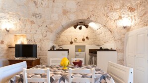 Una habitación acogedora con pared de piedra, una cama con colcha estampada, un televisor y una pequeña cocina.