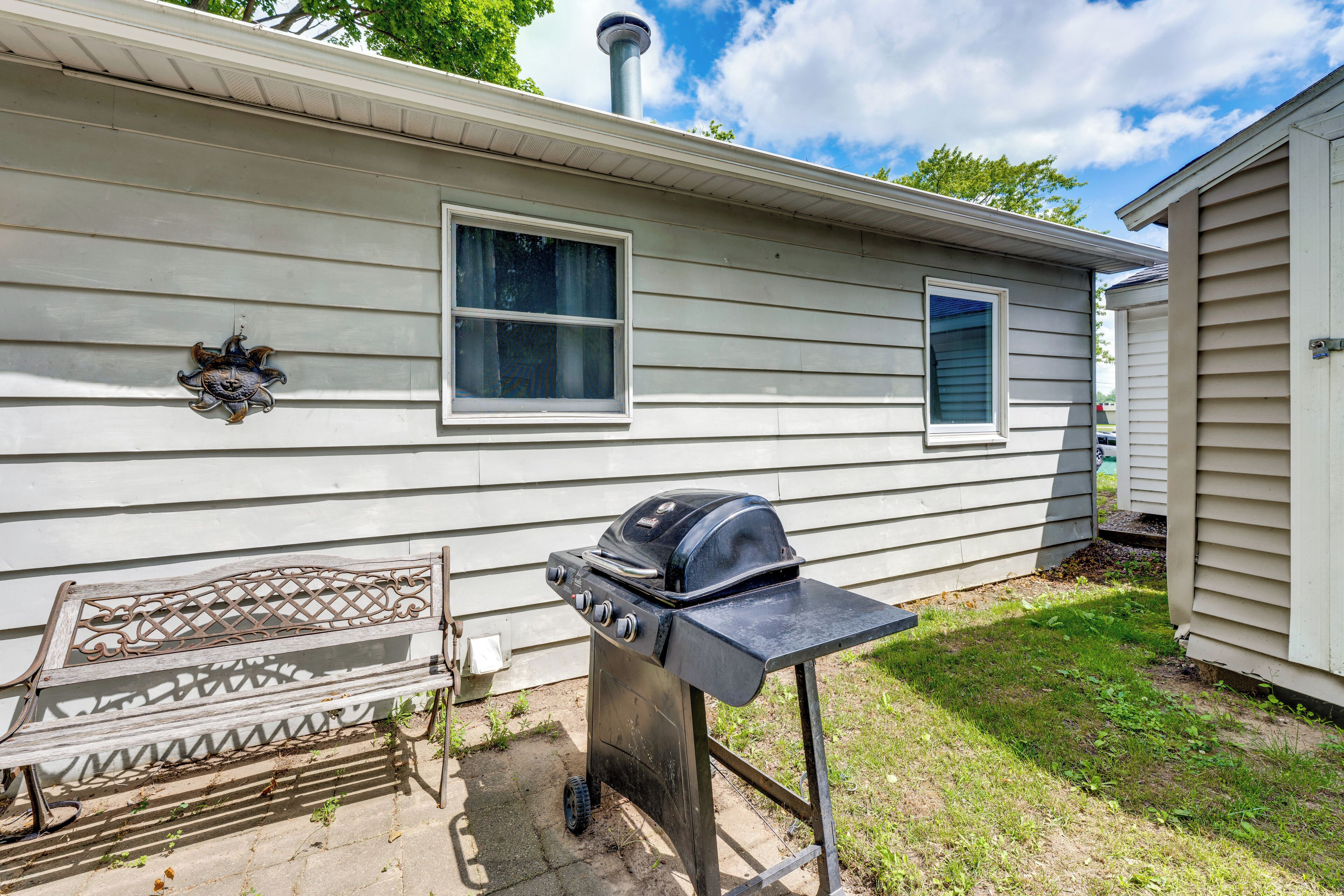 A portable grill and a bench outside a mobile home.