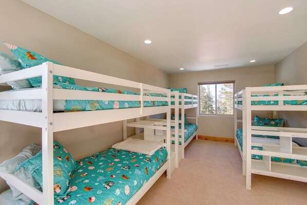 A room with bunk beds, a window, and a carpeted floor.