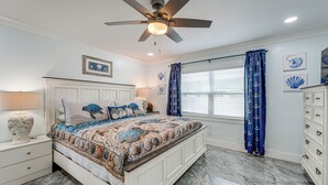 A bedroom with a bed, a ceiling fan, a nightstand, a dresser, and a window with curtains. - Steps to Madeira Beach! Modern Family Getaway (Madeira Beach)